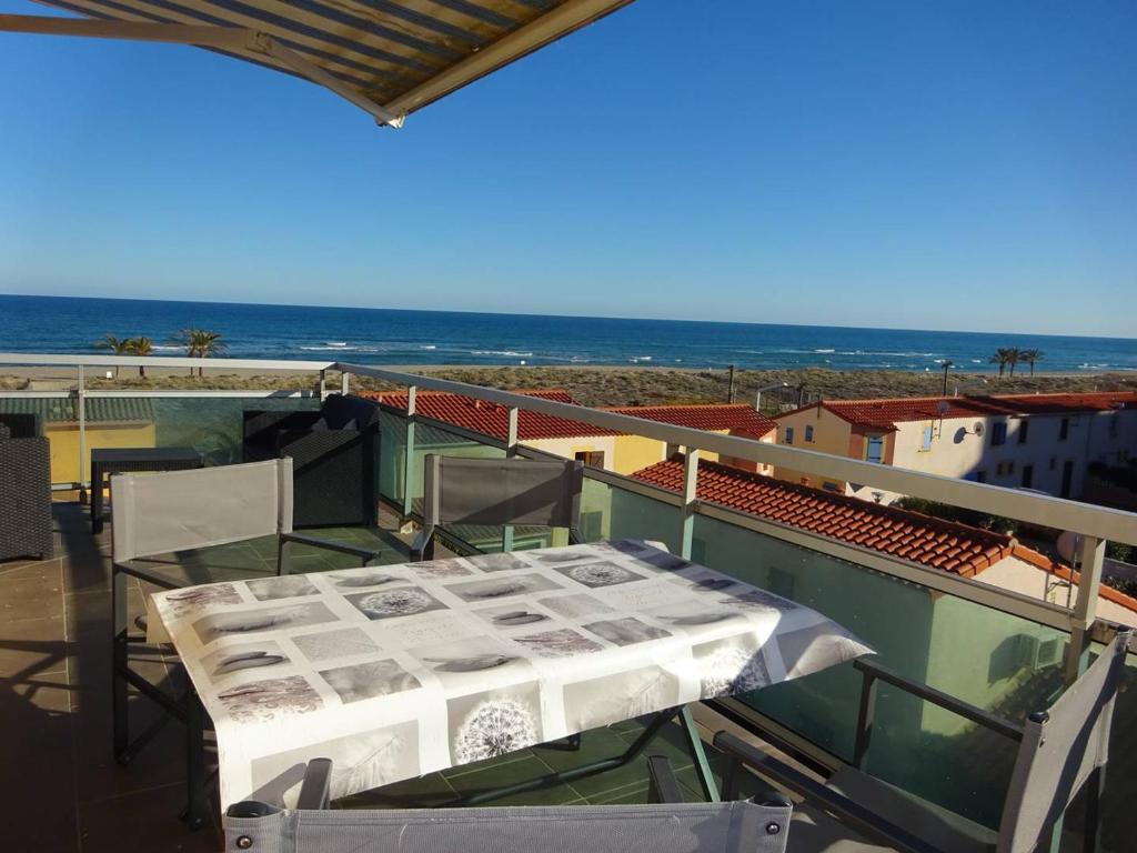 un balcon avec une table et des chaises et l'océan dans l'établissement Appartement climatisé près de la plage avec parking - 4/5 personnes - FR-1-782-2, au Barcarès