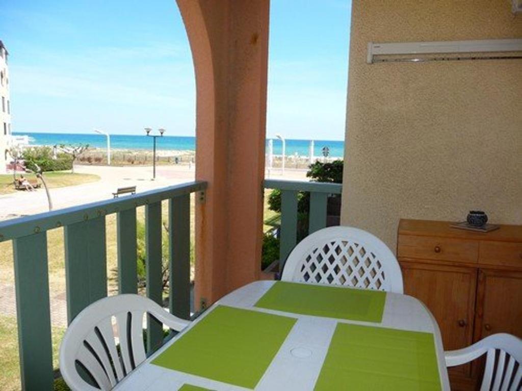 une table et des chaises sur un balcon avec la plage dans l'établissement Appartement rénové proche plage avec terrasse et parking privé - FR-1-782-24, au Barcarès