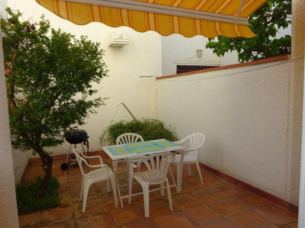 un patio avec une table, des chaises et un barbecue dans l'établissement Appartement T2 moderne, près de la plage, terrasse équipée, parking privé - Le Barcarès - FR-1-782-27, au Barcarès