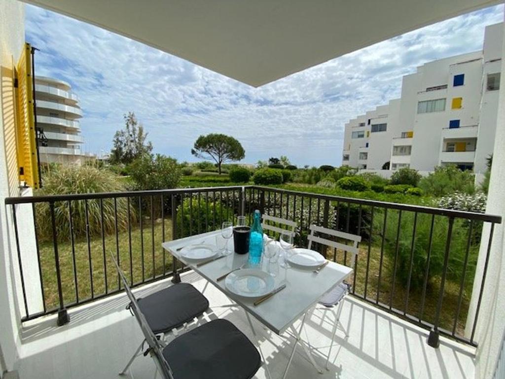 une table blanche et des chaises sur un balcon avec vue dans l'établissement Appartement rénové 2P à 100m de la plage avec parking privé - FR-1-782-30, au Barcarès
