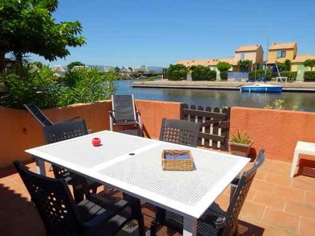 - une table et des chaises blanches avec vue sur la rivière dans l'établissement Villa 3 chambres avec parking privé proche plage et commerces - FR-1-782-35, au Barcarès