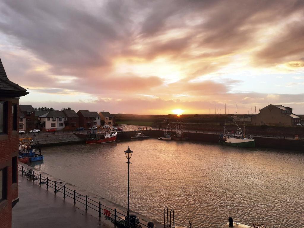 a sunset over a river with boats in it at Harbour Side in Maryport