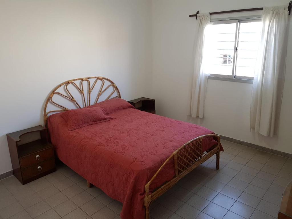 a bedroom with a bed with a redspread and a window at Casa en La Punta - San Luis in La Punta