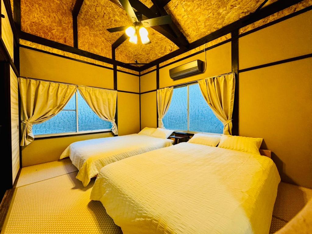 duas camas num quarto com duas janelas em 風乃家 Kaze No Ya em Shirahama