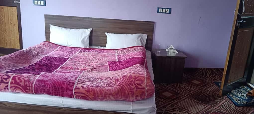 - une chambre avec un grand lit et une couverture rose dans l'établissement Apple Garden View and Restaurant, à Pahalgām