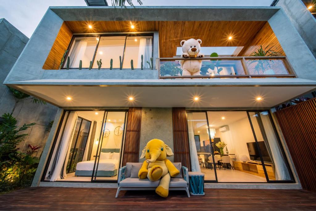 a yellow teddy bear sitting on a couch in front of a house at Sunny Village Berawa in Canggu