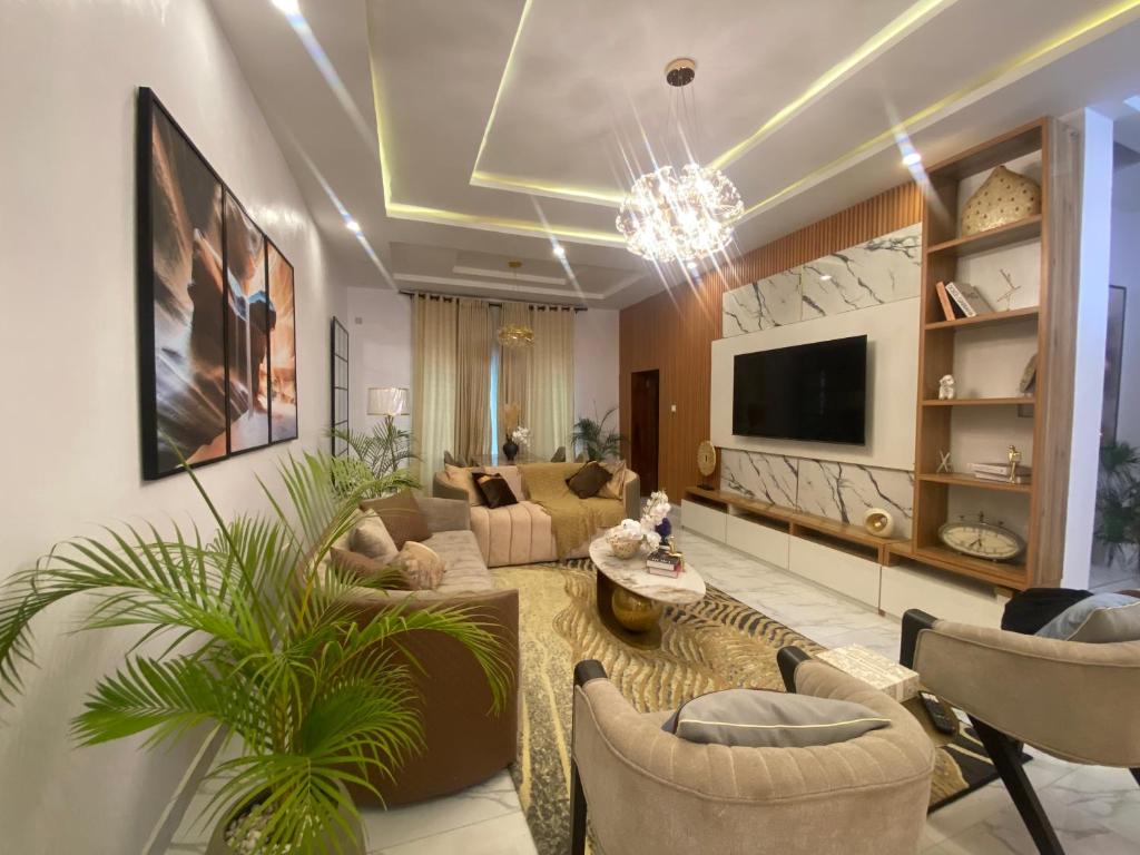 een woonkamer met een bank en stoelen en een tv bij Absl Luxury Apartments in Lekki