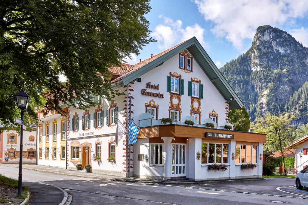 un edificio en una calle frente a una montaña en Zum Turm - Apartments und Gästezimmer en Oberammergau