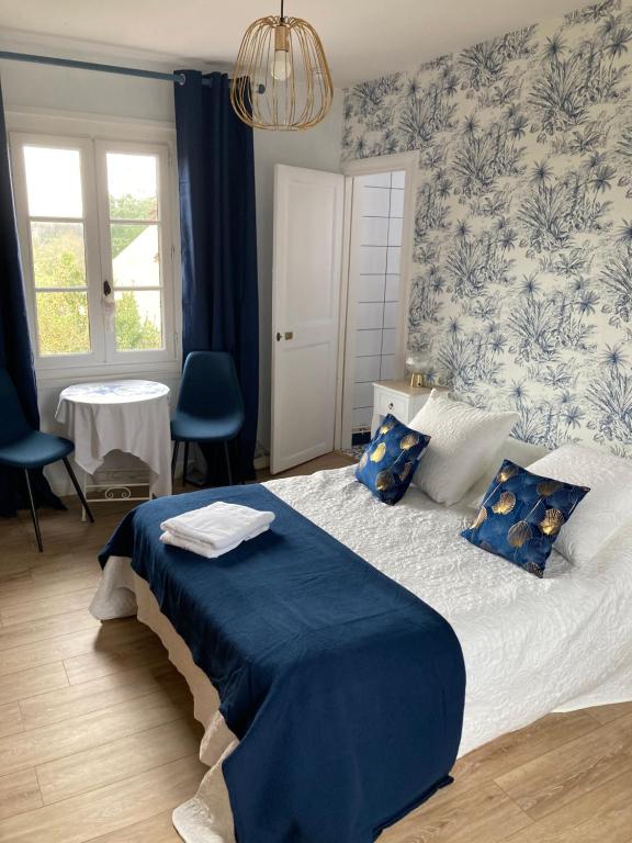 エクモヴィルにあるLes chambres d'hôtes Le Val d'Honfleurの青と白のベッドルーム(青のシーツが備わるベッド付)