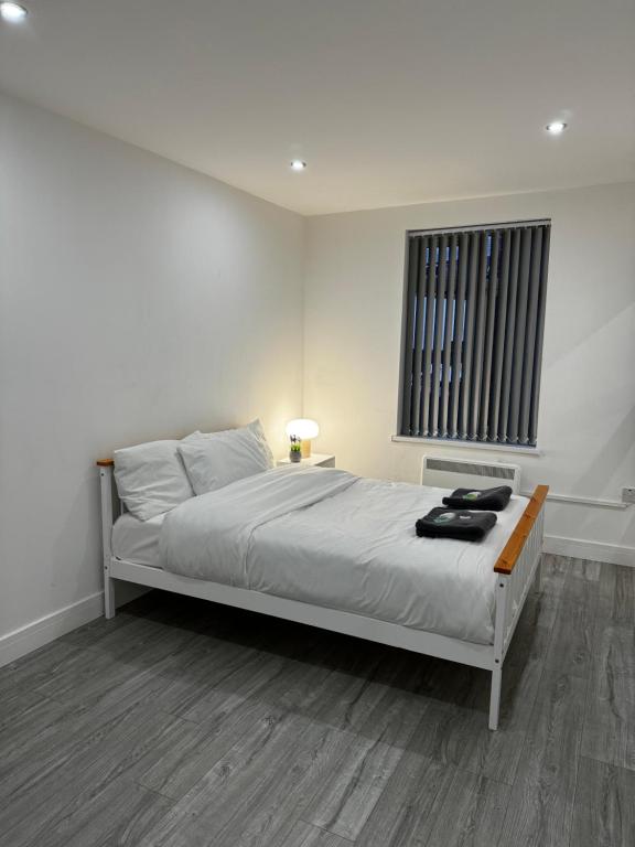 een witte slaapkamer met een bed en een raam bij Rooms Near Me - Apartment 1, Sky Tv, Free Parking 