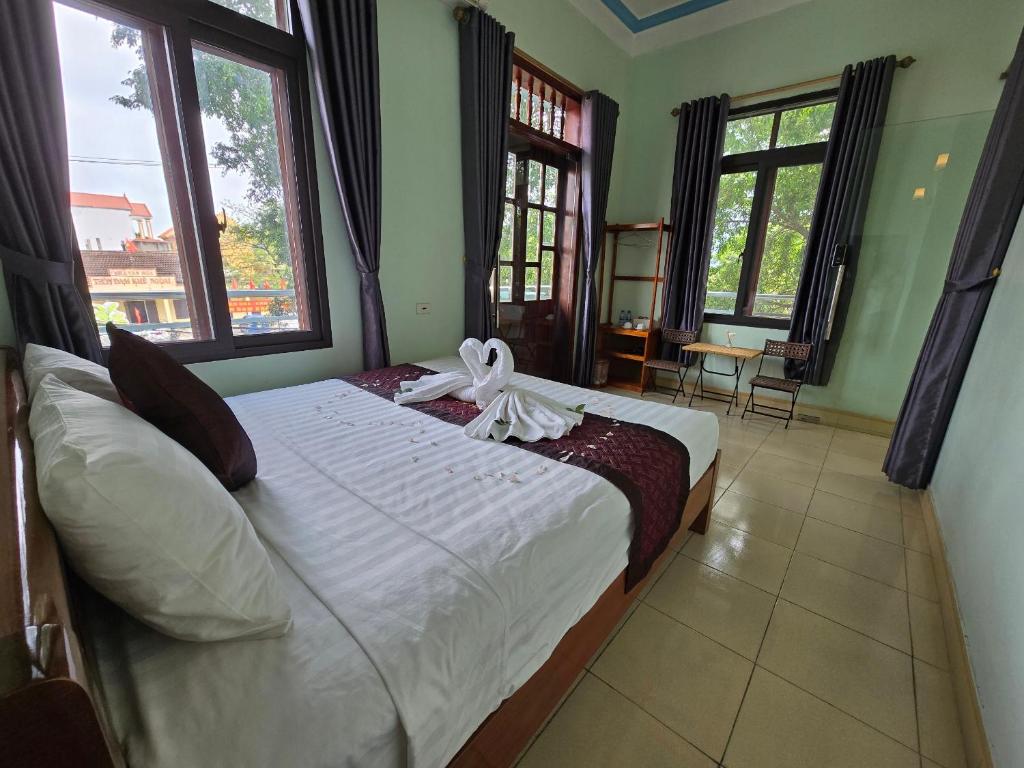 een slaapkamer met een bed met witte lakens en ramen bij Vi TamCoc Hotel in Ninh Binh