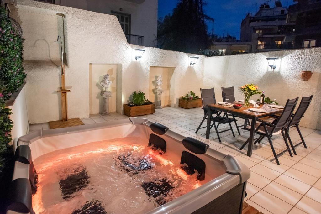 a jacuzzi tub in a patio with a table at KG Acropolis Escape Spa Apartment in Athens