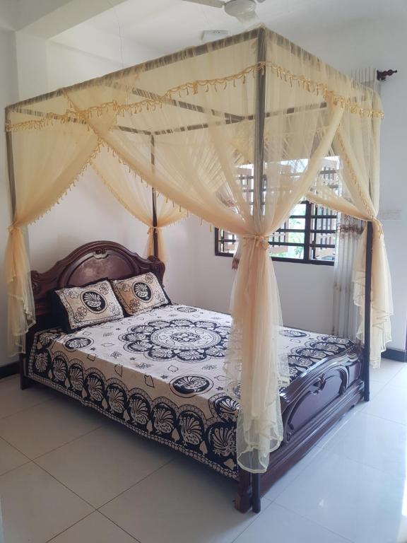 a bedroom with a canopy bed with curtains at Kabalana Ocean Blue in Ahangama