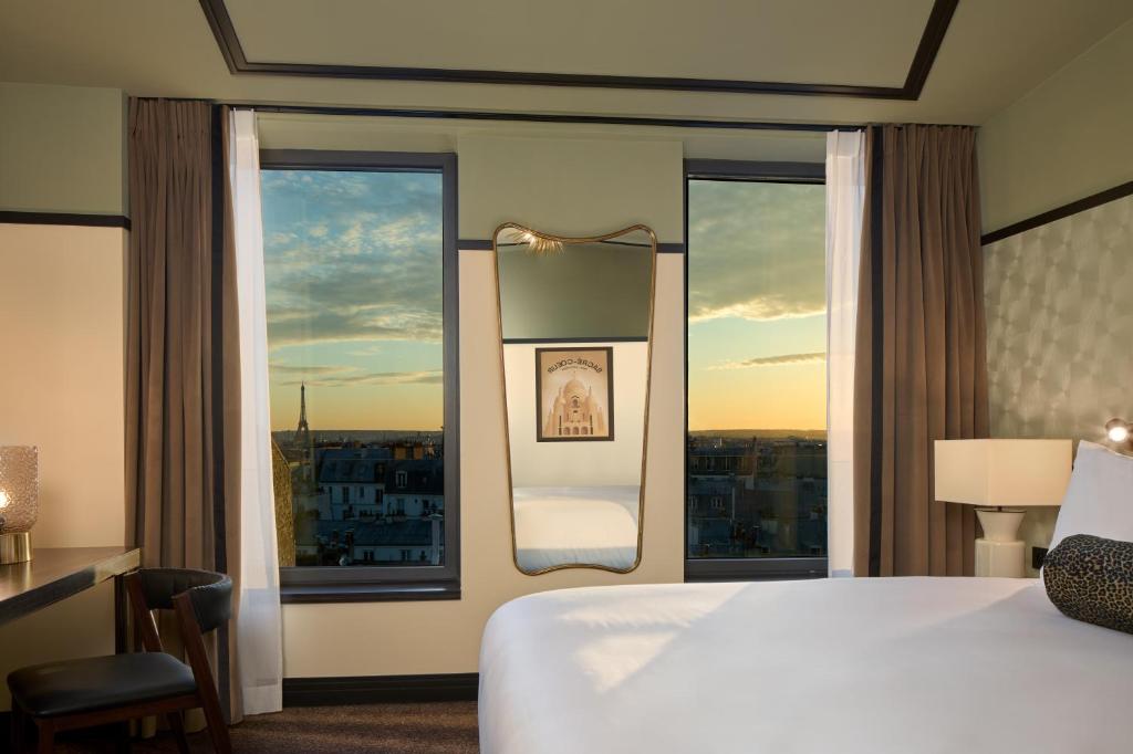 pokój hotelowy z łóżkiem i dużym oknem w obiekcie Maison Cassandre w Paryżu