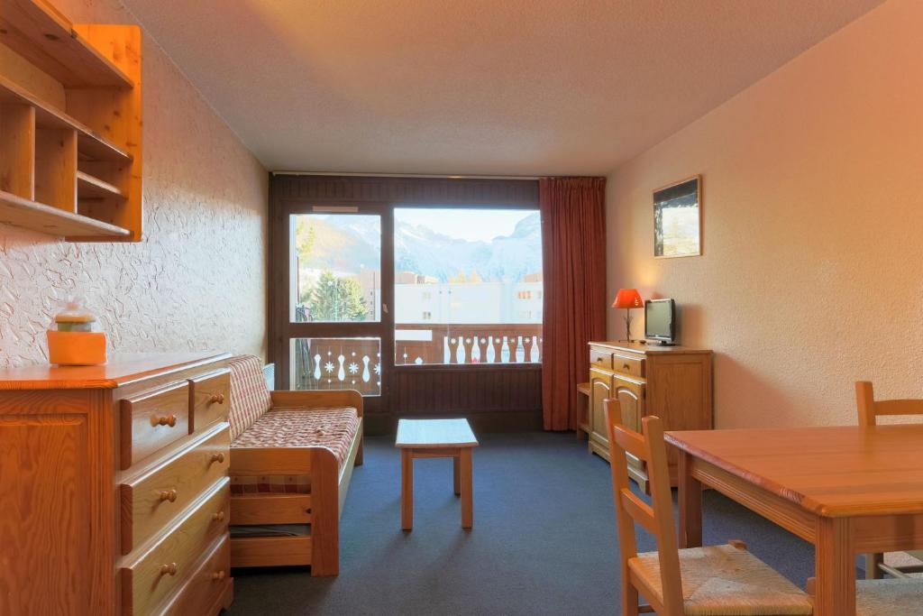 Cette chambre comprend une table, une fenêtre, une table et des chaises. dans l'établissement Plein Sud - 3106 - Studio pied des pistes - 4 pers, à Les Deux Alpes