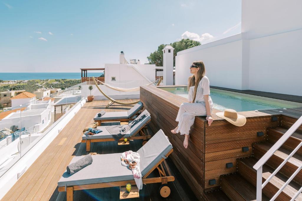 卡拉索斯的住宿－Kalathos Square luxury suites，坐在游艇上阳台边缘的女人