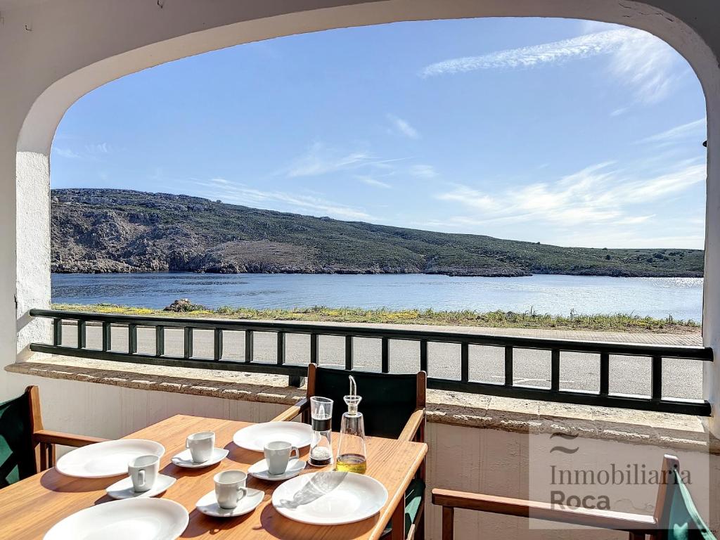 een tafel met stoelen en uitzicht op het water bij Roca Fornells, Apartamento en Tramontana F239 in Fornells