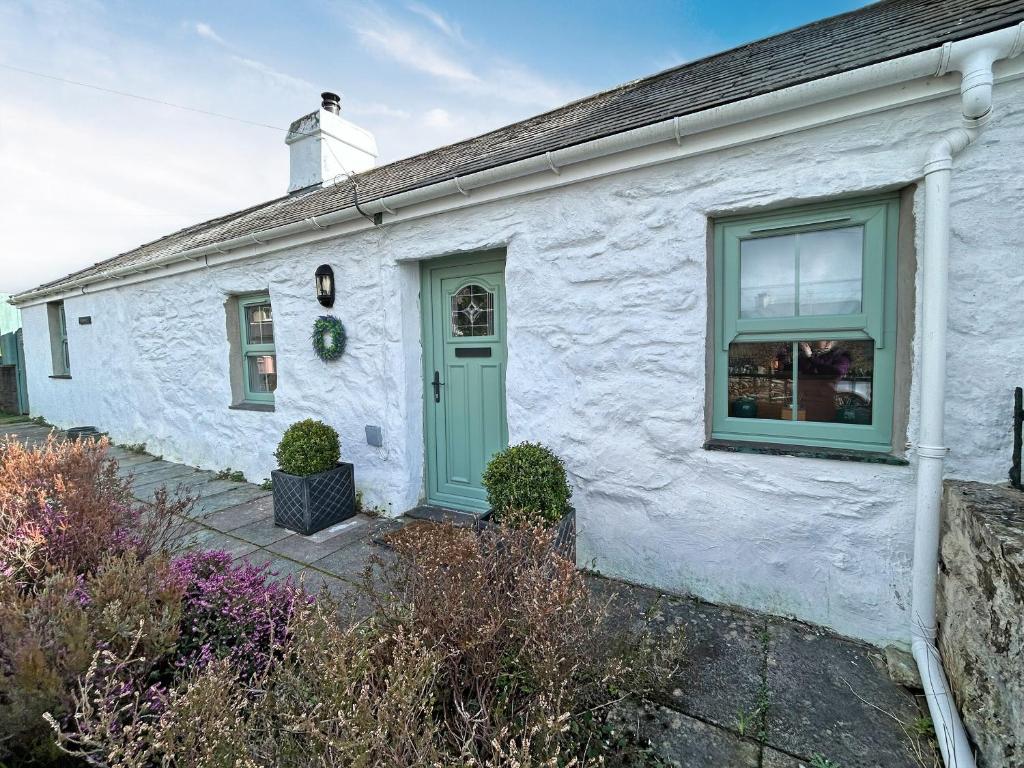 a white house with a green door at Lyndene Cottage in Moel-tryfan