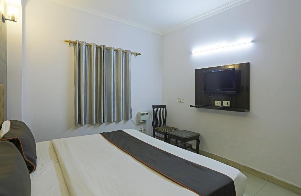 a hotel room with a bed and a tv at Airport KINGDOM in New Delhi