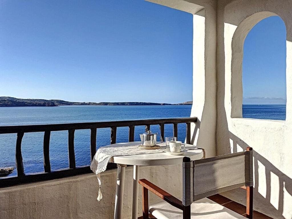 een tafel en stoel op een balkon met uitzicht op het water bij P98 - Bonito apartamento sobre el mar in Fornells