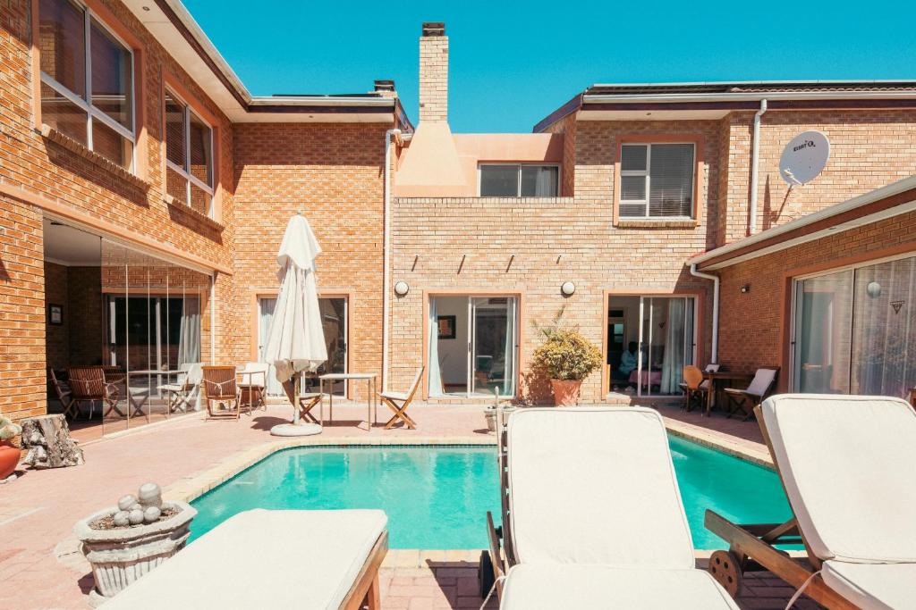 un patio trasero con piscina y muebles de exterior en Sunset Residence, en Ciudad del Cabo