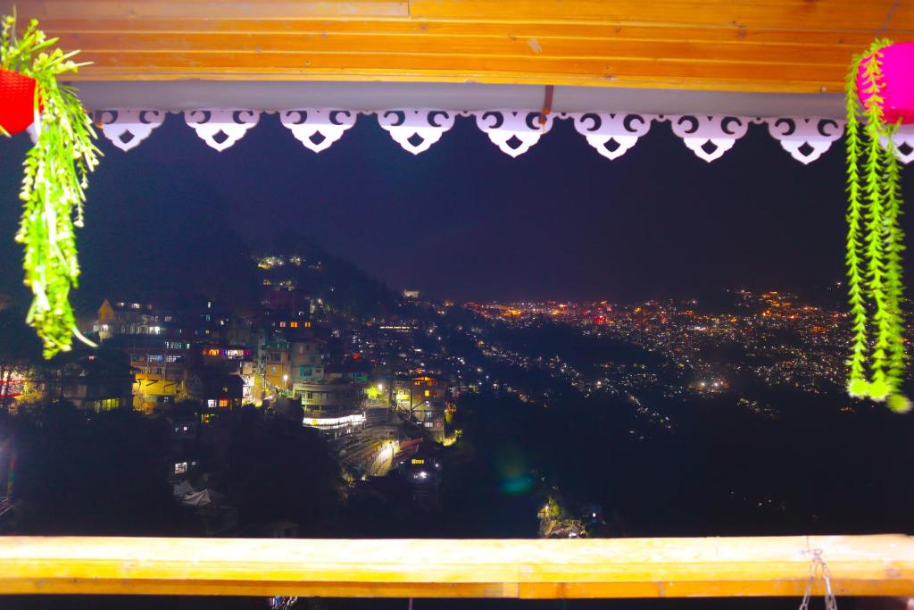 a window with a view of a city at night at Hotel Mountain Meadows in Darjeeling