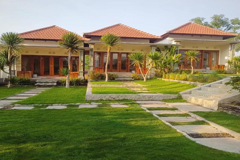 a house with a green yard with palm trees at Onion Garden And Natural Hotspring in Kubupenlokan