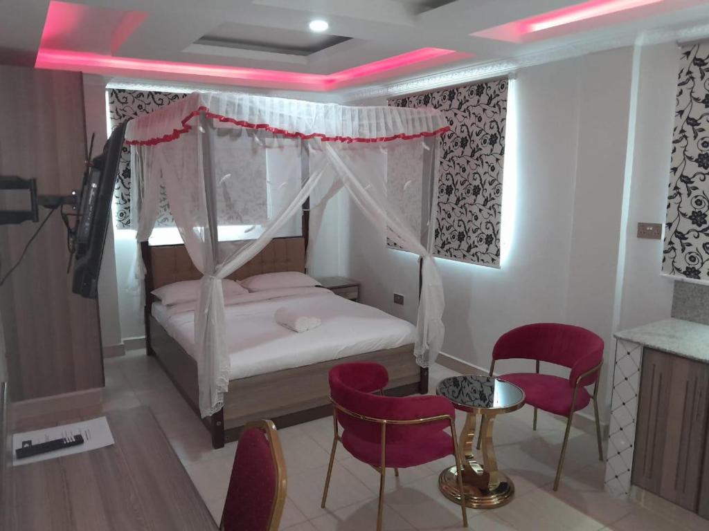 a bedroom with a canopy bed and red chairs at Equine Hotel in Ruiru