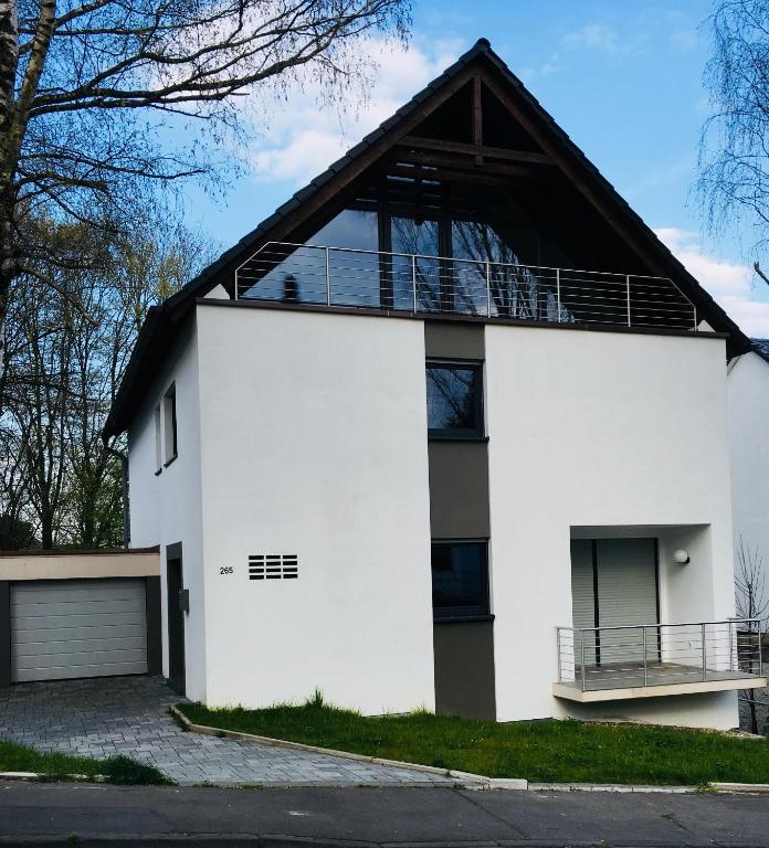 una casa blanca con techo de gambrel en Modernes Ferienhaus mit 2 Balkonen, Terrasse und Garten !, en Bochum