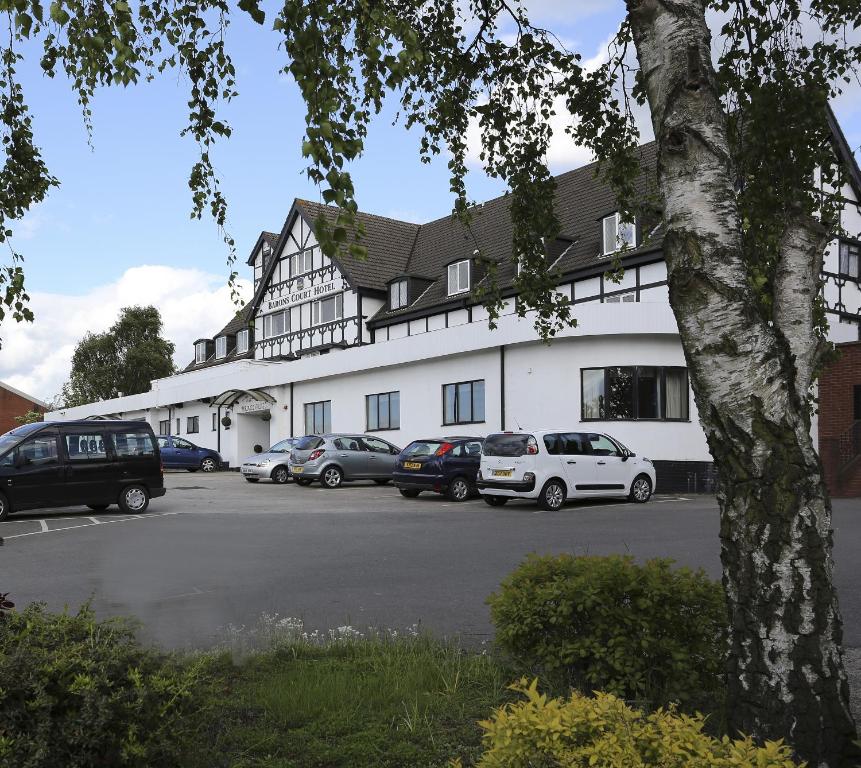un grand bâtiment blanc avec des voitures garées dans un parking dans l'établissement Barons Court Hotel Walsall, à Walsall