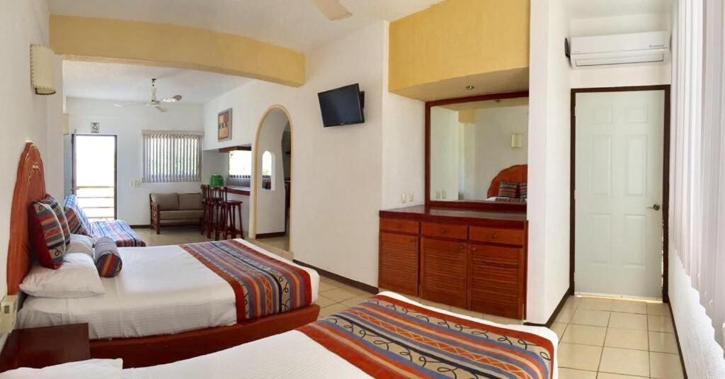 a hotel room with two beds and a mirror at Quinta Carrizalillo in Puerto Escondido