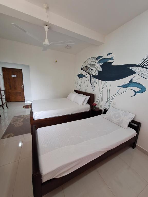 duas camas num quarto com um mural na parede em Baden Beach em Kalkudah