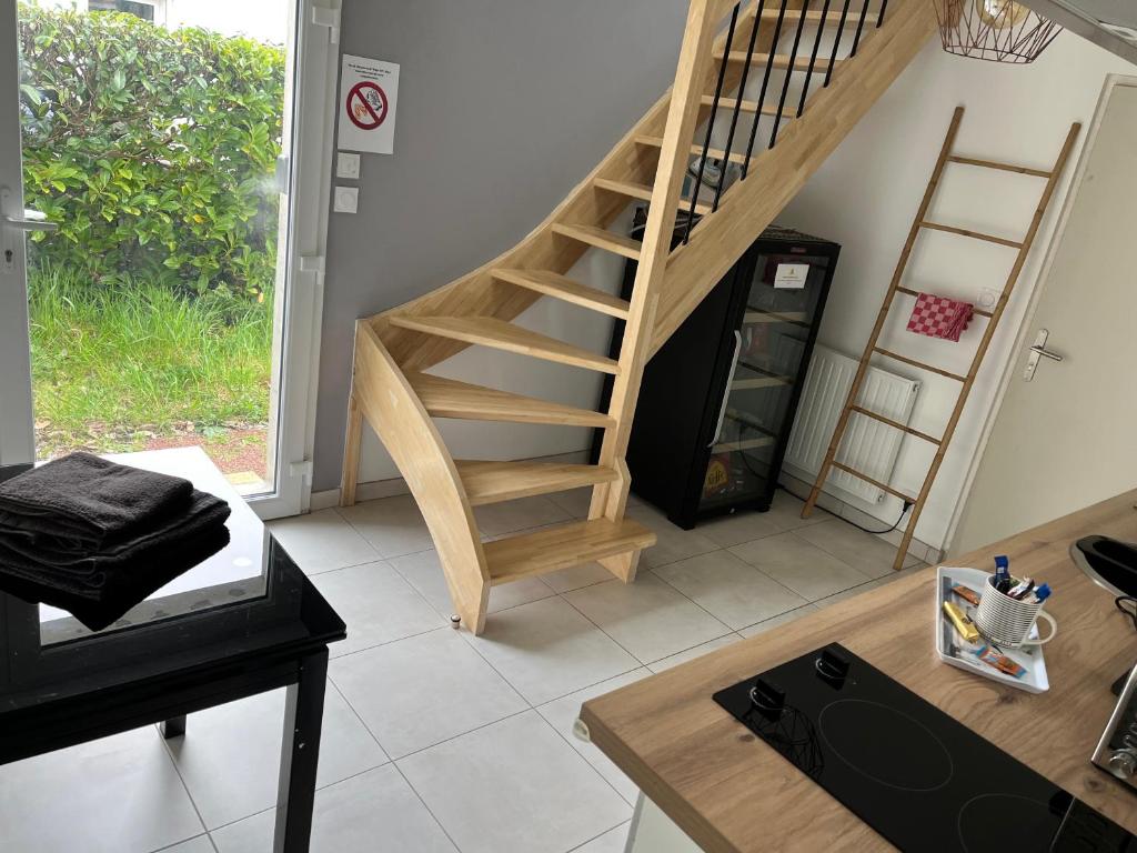 a wooden staircase in a living room with a table at STUDIO proche aéroport in Bouguenais
