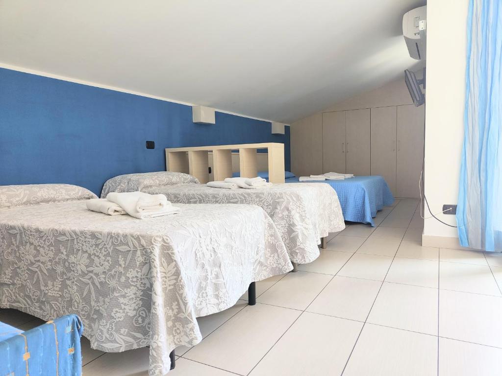 two beds in a room with blue walls and white floors at Rooms&Apartments Hotel Danci in Borghetto Santo Spirito