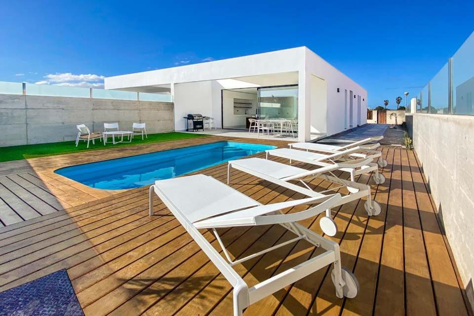 a row of lounge chairs on the deck of a house at LEA LUXURY GOLF HOUSE in Caleta De Fuste