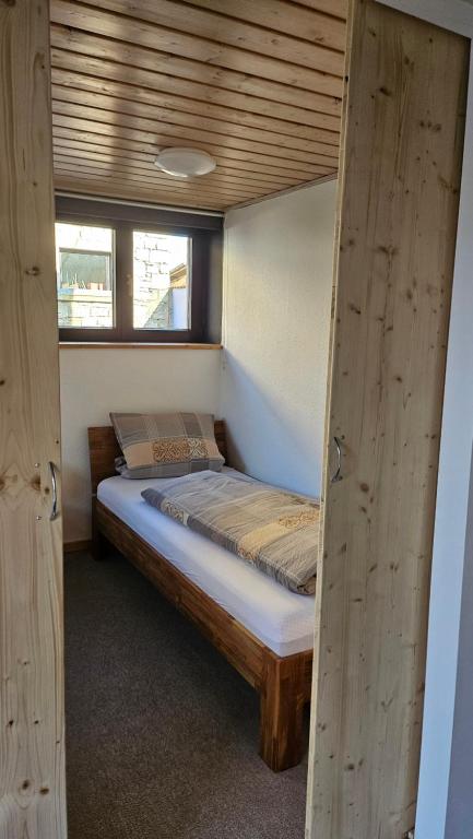 a small bed in a room with two windows at Haus Ela 