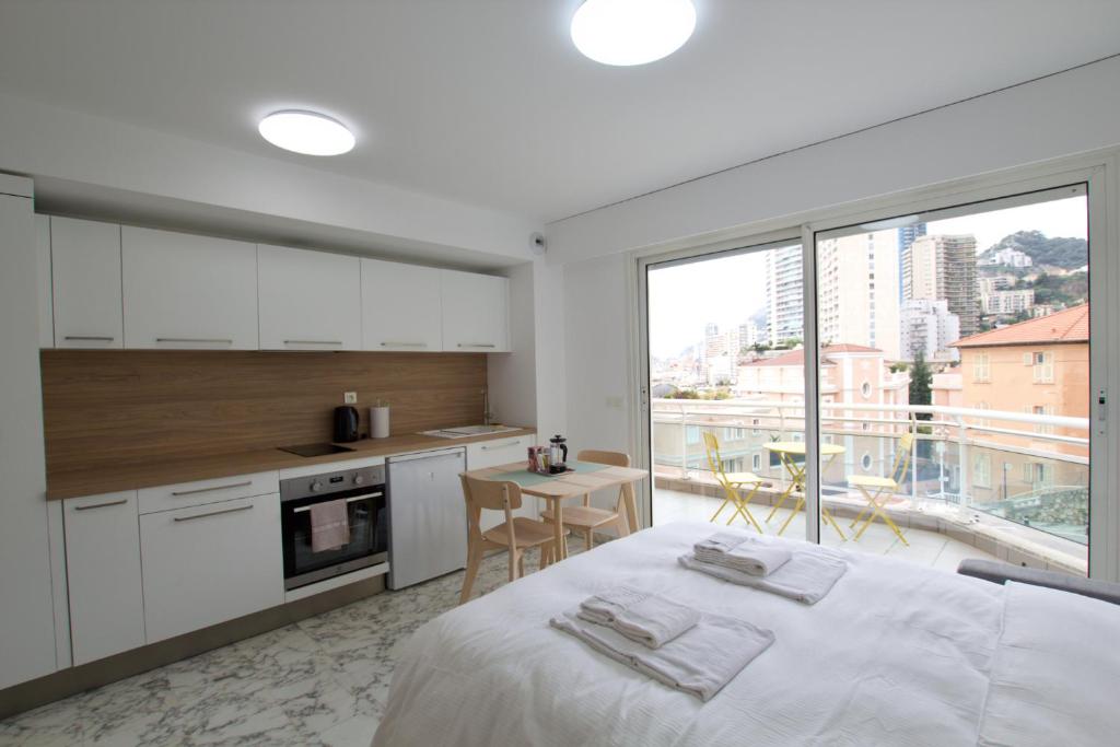 ein Schlafzimmer mit einem Bett und eine Küche mit einem großen Fenster in der Unterkunft Cosy studio aperçu mer Monaco border in Beausoleil