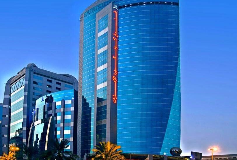 ein hohes blaues Gebäude mit Palmen davor in der Unterkunft ROYAL CONCORDE HOTEL&SUITE in Dubai