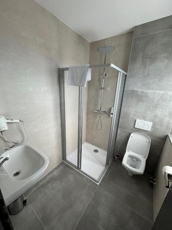 a bathroom with a shower and a toilet and a sink at F Hotel in Hörsching