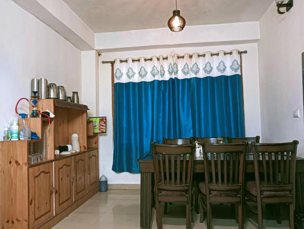 a dining room with a blue curtain and a table and chairs at The White House Shimla in Shimla