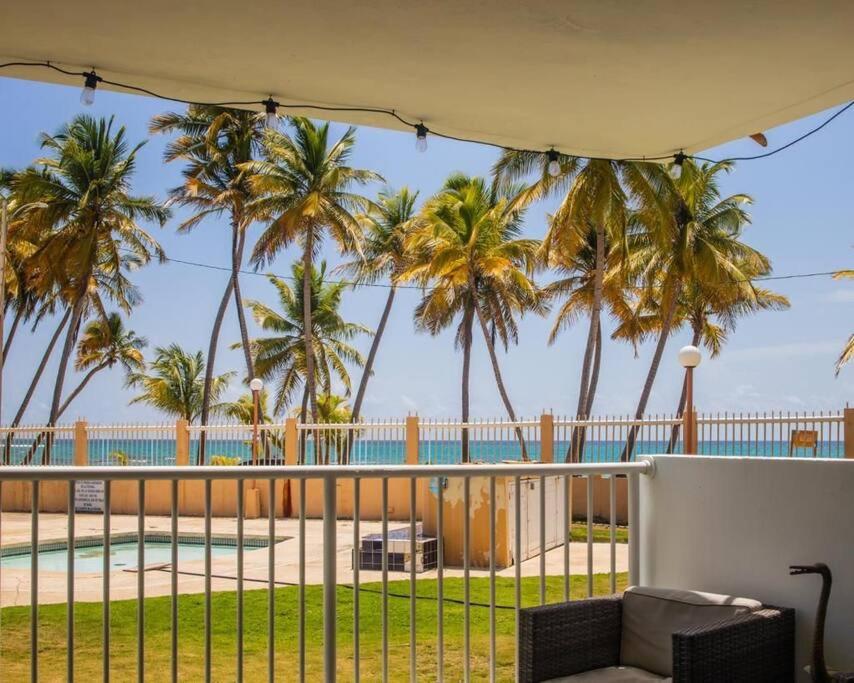 a patio with palm trees and a swimming pool at Ocean Blue Beach Apt in Luquillo