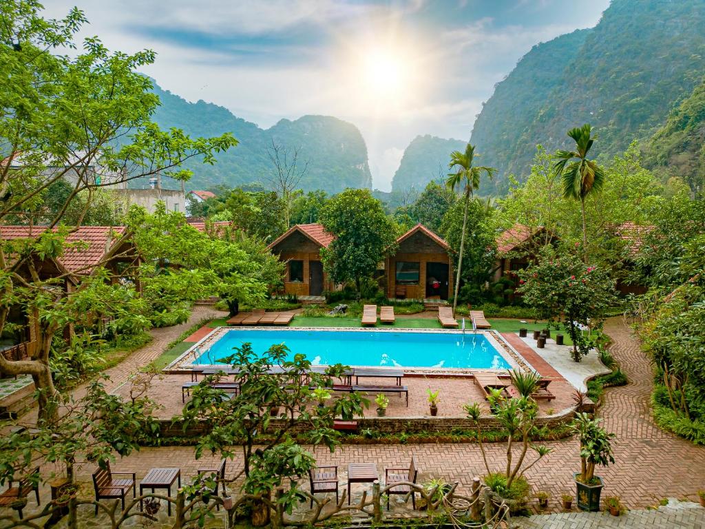 a resort with a pool and mountains in the background at Tam Coc Rocky Bungalow in Ninh Binh
