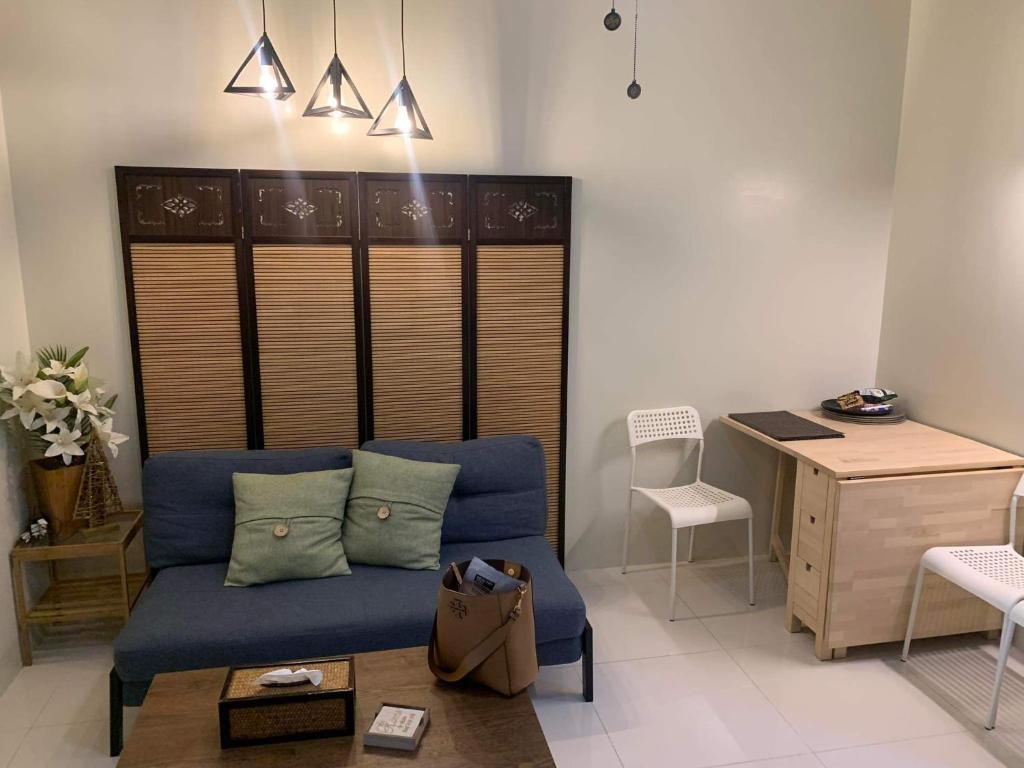Una sala de estar con un sofá azul y un escritorio. en Brenthill Condo (Sandstone Unit), en Baguio