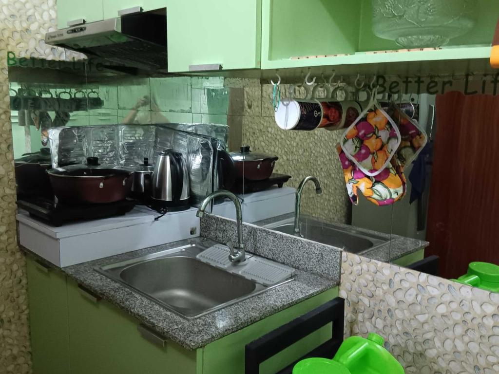 una cocina con fregadero y algunas ollas y sartenes en Paseo Verde Condominium en Manila