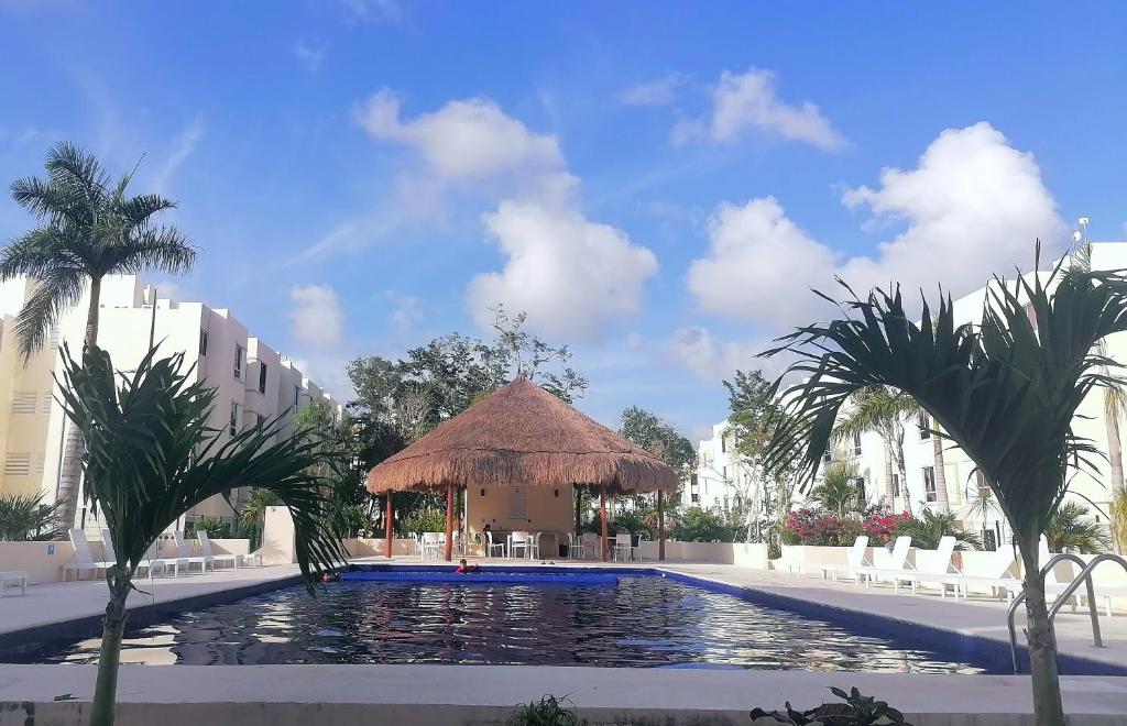 a swimming pool with a gazebo and palm trees at La puerta gris in Tulum