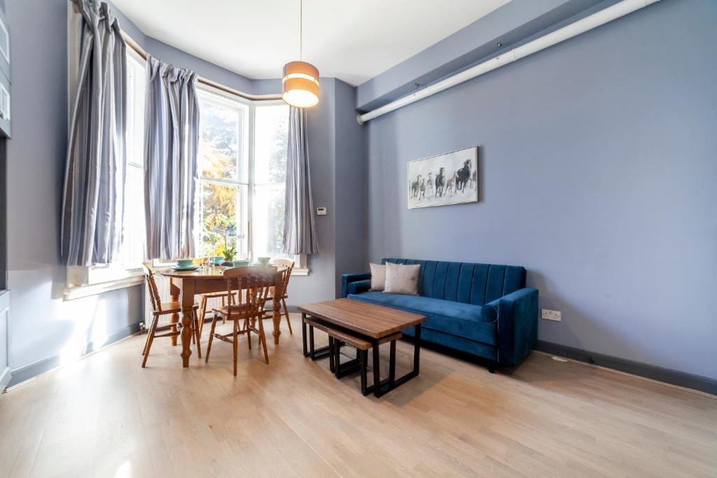 a living room with a blue couch and a table at Couple's getaway 1BDR apt near Holland Park in London
