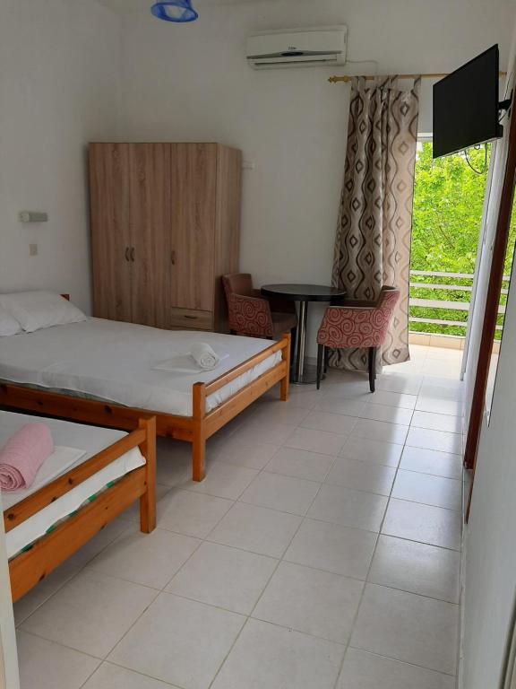 a room with two beds and a tv and a table at STUDIOS MONA in Agios Georgios