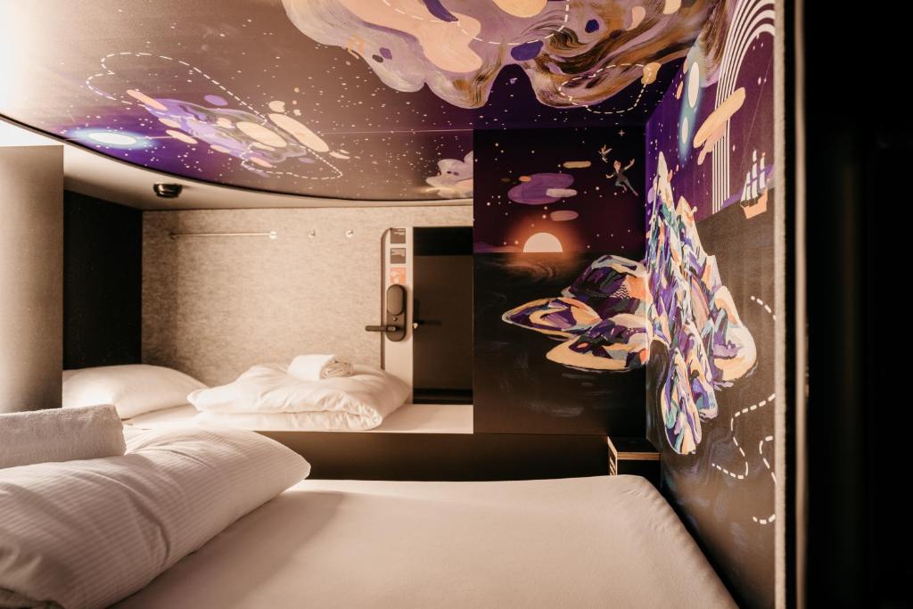 2 Betten in einem Zimmer mit Wandgemälde in der Unterkunft Capsule Hotel - Chapter Lucerne in Luzern