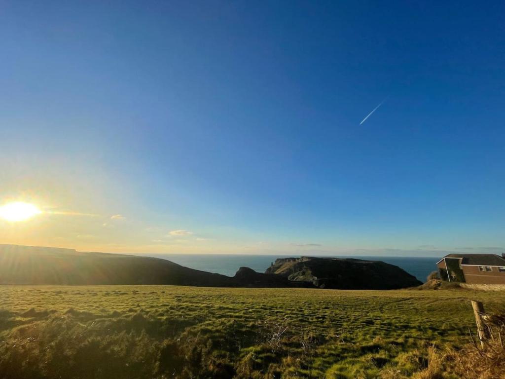 una vista su un campo con il sole nel cielo di Pendragon Uninterrupted coastal views a Tintagel