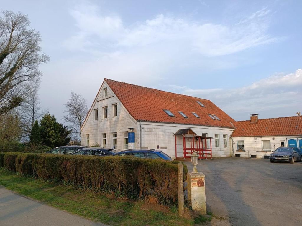 a large white house with cars parked in a parking lot at Ferienwohnung Leuchtturm - b51002 in Oldenswort